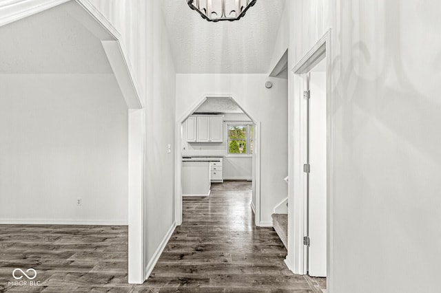 hallway with stairs, dark wood-style flooring, baseboards, and an inviting chandelier