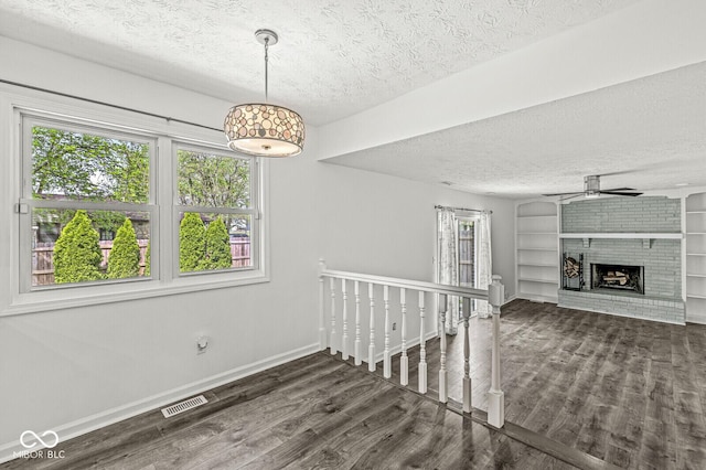 interior space with baseboards, visible vents, a textured ceiling, and wood finished floors