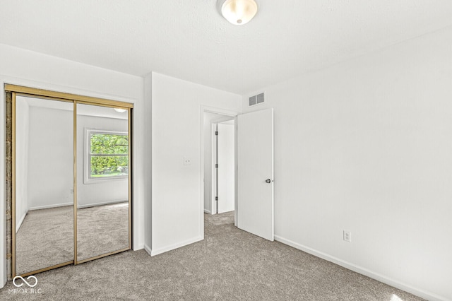 unfurnished bedroom with visible vents, baseboards, carpet floors, and a closet