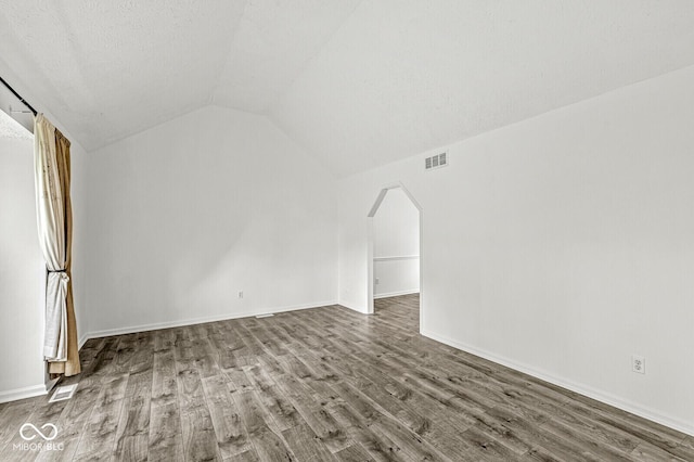 interior space with vaulted ceiling, wood finished floors, and visible vents