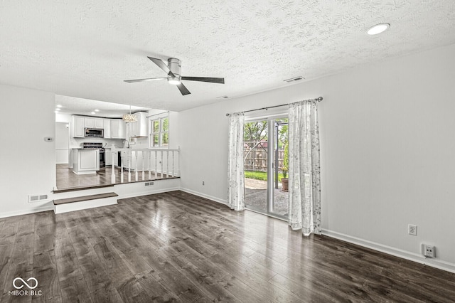 unfurnished living room featuring visible vents, a ceiling fan, a textured ceiling, and dark wood-style floors