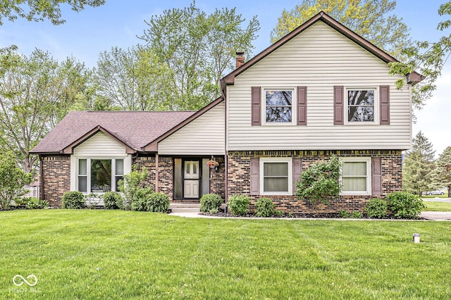 split level home featuring a chimney, a front yard, and brick siding