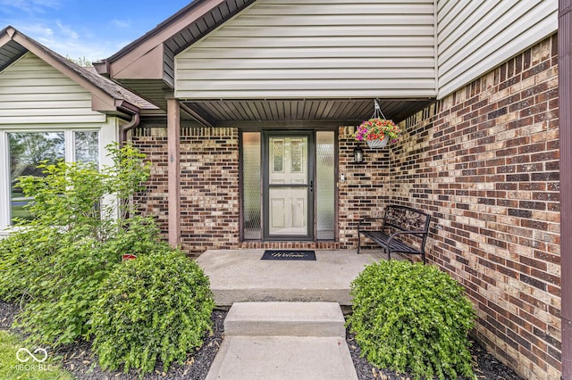 view of exterior entry with covered porch and brick siding