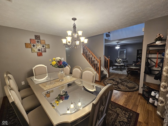 dining area featuring ceiling fan with notable chandelier, wood finished floors, and stairway