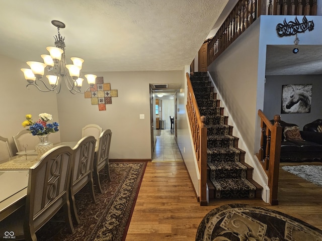 interior space featuring a textured ceiling, baseboards, wood finished floors, and a chandelier