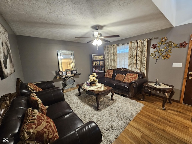 living room with baseboards, a textured ceiling, ceiling fan, and wood finished floors