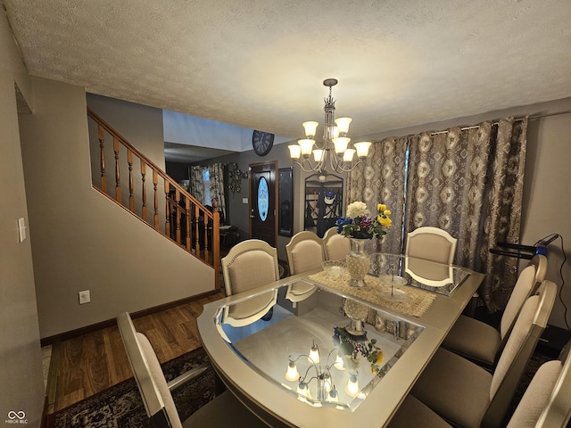 dining area featuring a textured ceiling, a chandelier, baseboards, wood finished floors, and stairway