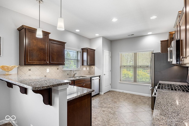 5136 Centerview Dr, Battle Ground, IN 47920 - kitchen with dark brown cabinets, a kitchen breakfast bar, tasteful backsplash, a sink, and stainless steel appliances