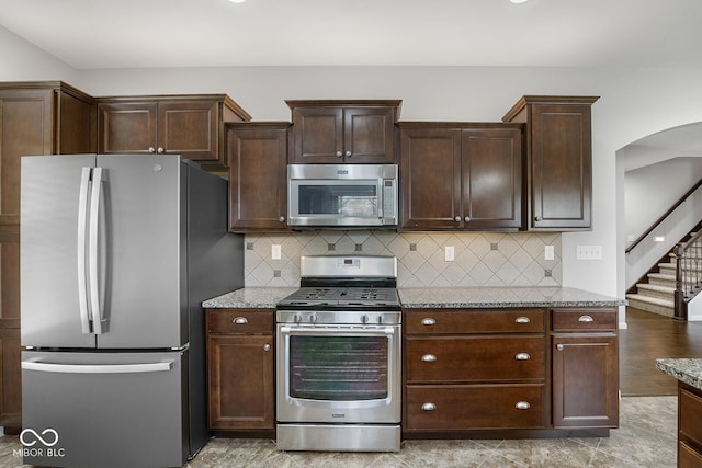 5136 Centerview Dr, Battle Ground, IN 47920 - kitchen with dark brown cabinets, light stone countertops, appliances with stainless steel finishes, and decorative backsplash
