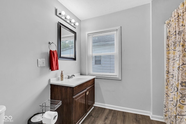 bathroom featuring vanity, toilet, a shower with shower curtain, baseboards, and wood finished floors