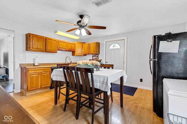 dining room with baseboards, ceiling fan, light wood finished floors, and visible vents