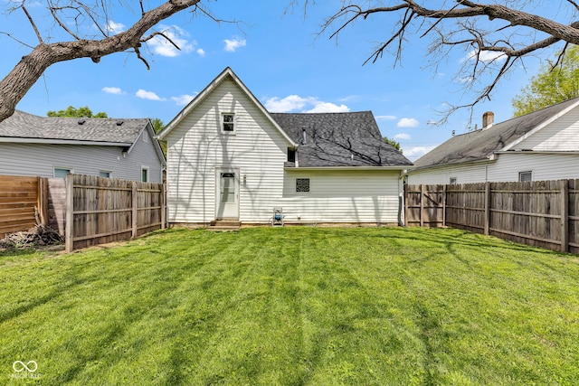 rear view of house with a lawn, a fenced backyard, and entry steps