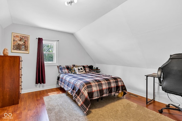 bedroom with baseboards, vaulted ceiling, and wood finished floors