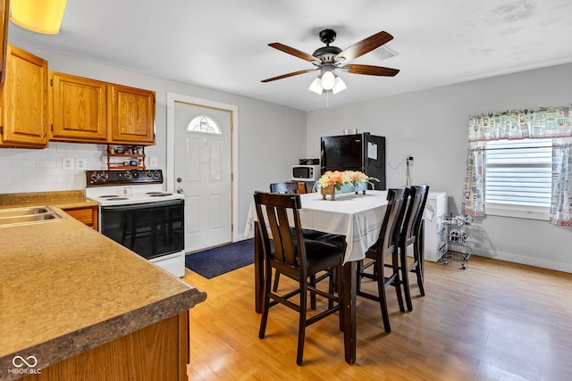 dining room featuring baseboards, ceiling fan, visible vents, and light wood-style flooring