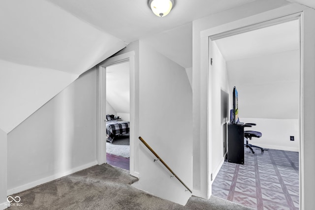 interior space featuring carpet flooring, baseboards, and vaulted ceiling
