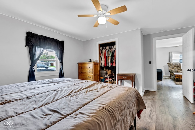 bedroom featuring a ceiling fan, baseboards, wood finished floors, and a closet