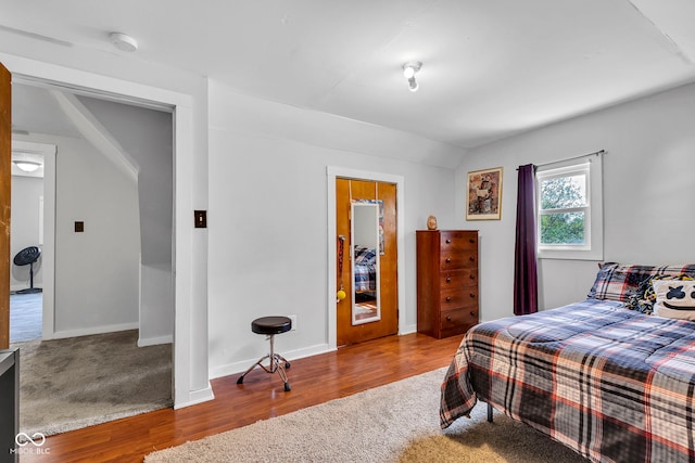 bedroom featuring baseboards, carpet flooring, wood finished floors, and lofted ceiling