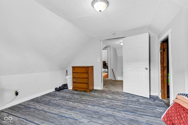 additional living space featuring baseboards, vaulted ceiling, and a textured ceiling