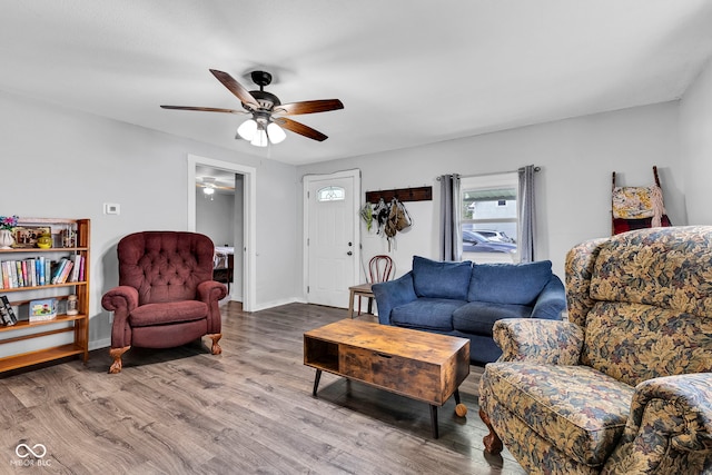 living area featuring baseboards, a ceiling fan, and wood finished floors