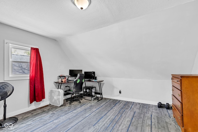 office featuring a textured ceiling, baseboards, wood finished floors, and lofted ceiling