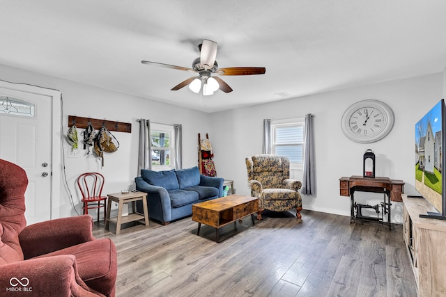 living room with a healthy amount of sunlight, ceiling fan, and dark wood-type flooring