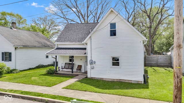 view of front facade with fence, a shingled roof, a porch, and a front lawn