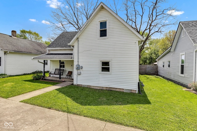 back of house featuring a yard, fence, a shingled roof, and covered porch