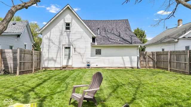 back of property featuring a lawn, a shingled roof, a fenced backyard, and entry steps