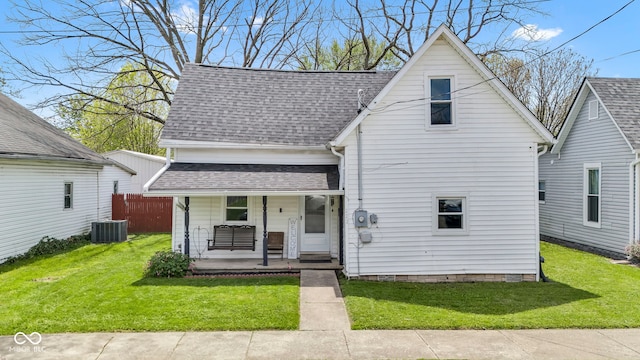 view of front of house with central air condition unit, covered porch, a shingled roof, and a front yard