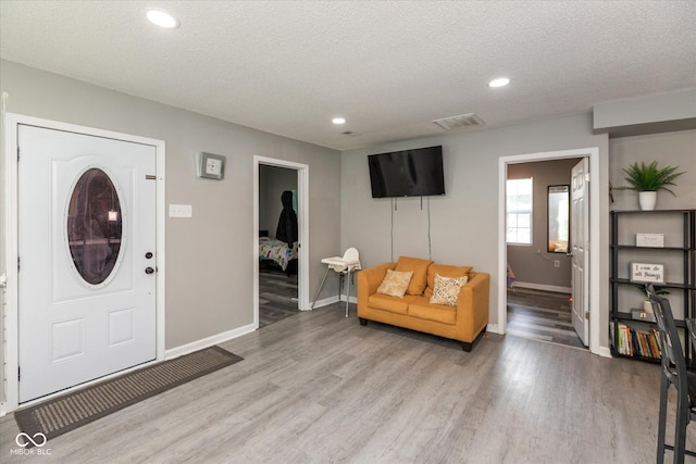 entrance foyer featuring a textured ceiling, light wood-style flooring, recessed lighting, baseboards, and visible vents