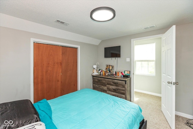 bedroom featuring a closet, baseboards, light colored carpet, and visible vents
