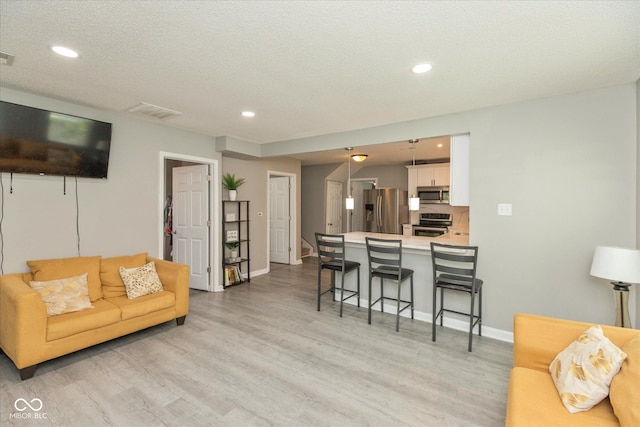 living room featuring light wood-type flooring, recessed lighting, baseboards, and visible vents