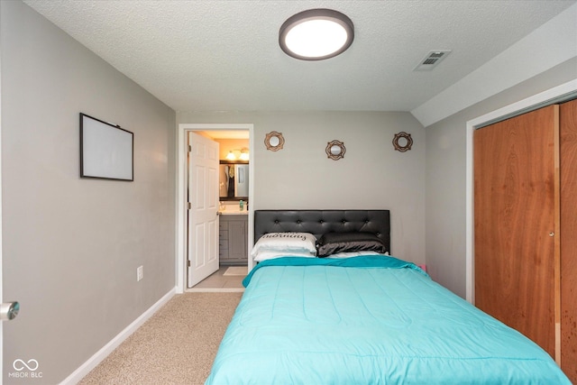 bedroom with a textured ceiling, visible vents, baseboards, ensuite bathroom, and light carpet