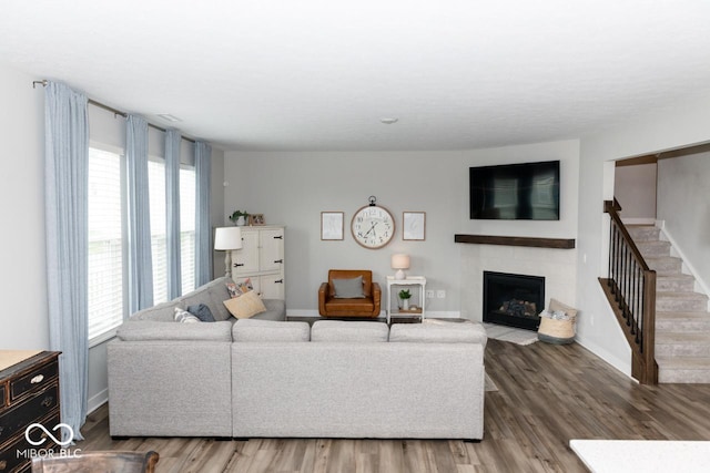 9176 Springbrook Dr, Pendleton, IN 46064 - living room featuring stairs, healthy amount of natural light, wood finished floors, and a fireplace with flush hearth
