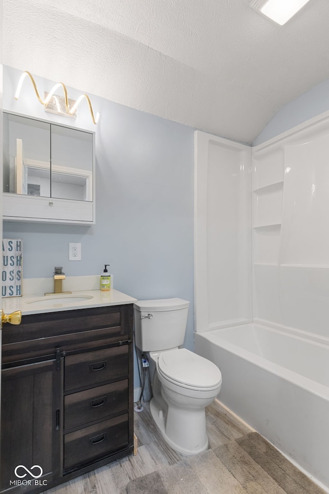 bathroom featuring vanity, lofted ceiling, wood finished floors, toilet, and a textured ceiling