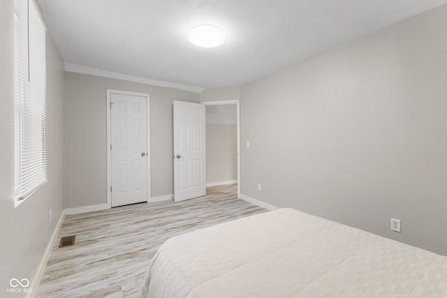 bedroom with visible vents, baseboards, and wood finished floors