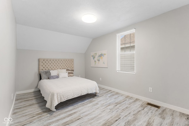 bedroom with baseboards, wood finished floors, and visible vents