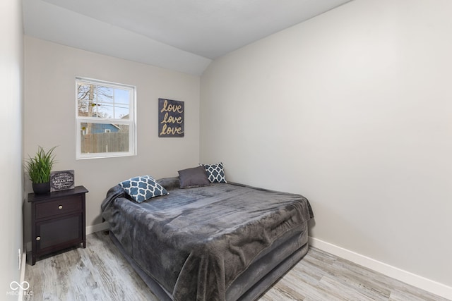 bedroom featuring baseboards, wood finished floors, and vaulted ceiling