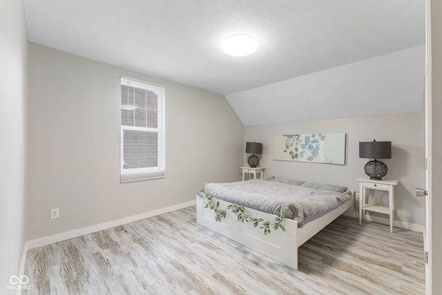 bedroom featuring baseboards, wood finished floors, and lofted ceiling