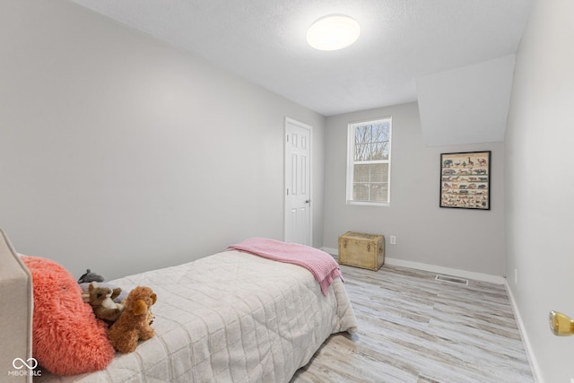 bedroom featuring baseboards, wood finished floors, and visible vents