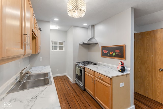 kitchen with baseboards, wall chimney range hood, stainless steel range with gas cooktop, recessed lighting, and a sink