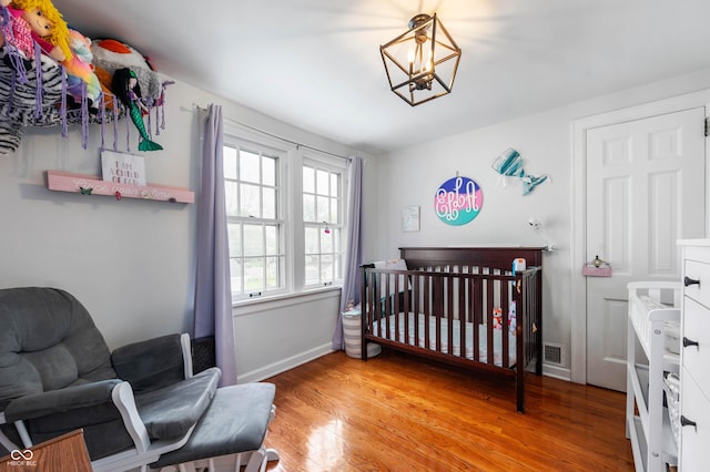155 N Franklin Rd, Indianapolis, IN 46219 - bedroom with a crib, light wood finished floors, a chandelier, baseboards, and visible vents