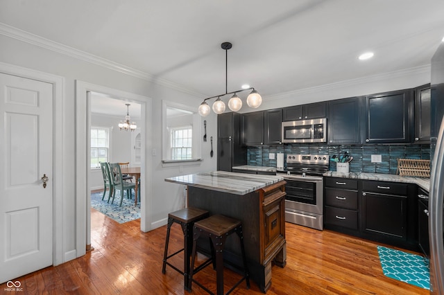155 N Franklin Rd, Indianapolis, IN 46219 - kitchen featuring a kitchen island, backsplash, a kitchen bar, light wood-type flooring, and stainless steel appliances