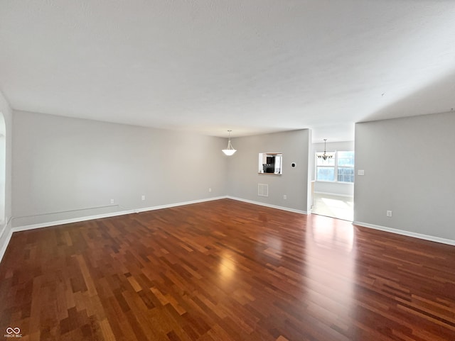 unfurnished living room with baseboards, dark wood-style flooring, and a chandelier
