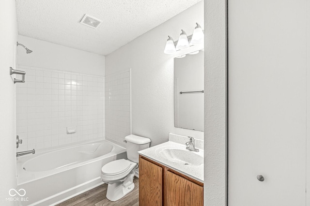 full bathroom with a textured ceiling, visible vents, wood finished floors, vanity, and toilet