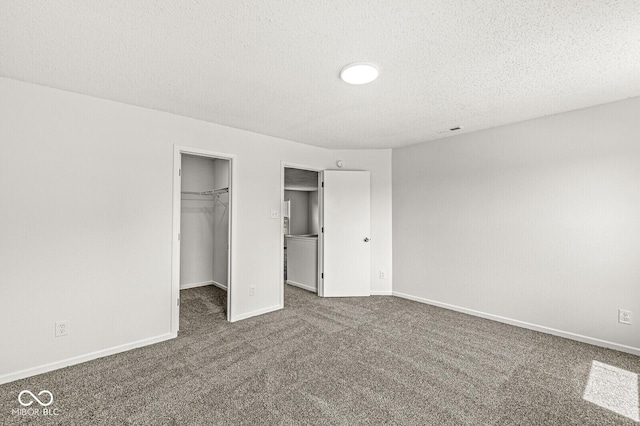 unfurnished bedroom with a walk in closet, carpet floors, a textured ceiling, baseboards, and a closet