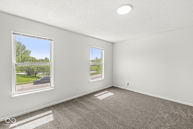 carpeted spare room featuring baseboards and a textured ceiling