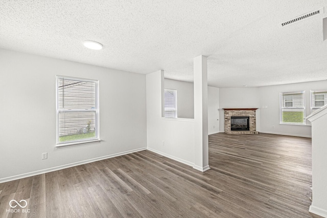 unfurnished living room with plenty of natural light, wood finished floors, and visible vents