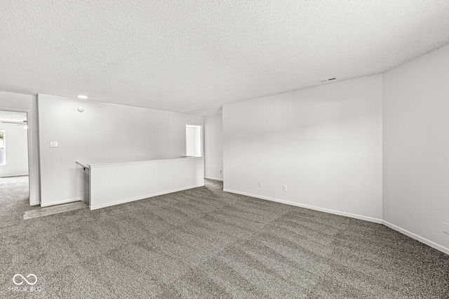 empty room featuring carpet floors, a textured ceiling, and baseboards