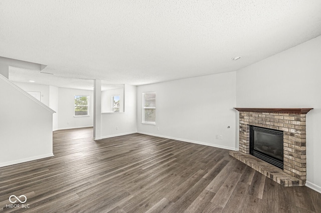 unfurnished living room with baseboards, a fireplace, dark wood finished floors, and a textured ceiling